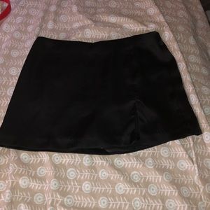 Black mini skirt with little slit in front, brand is Glam and size is small.